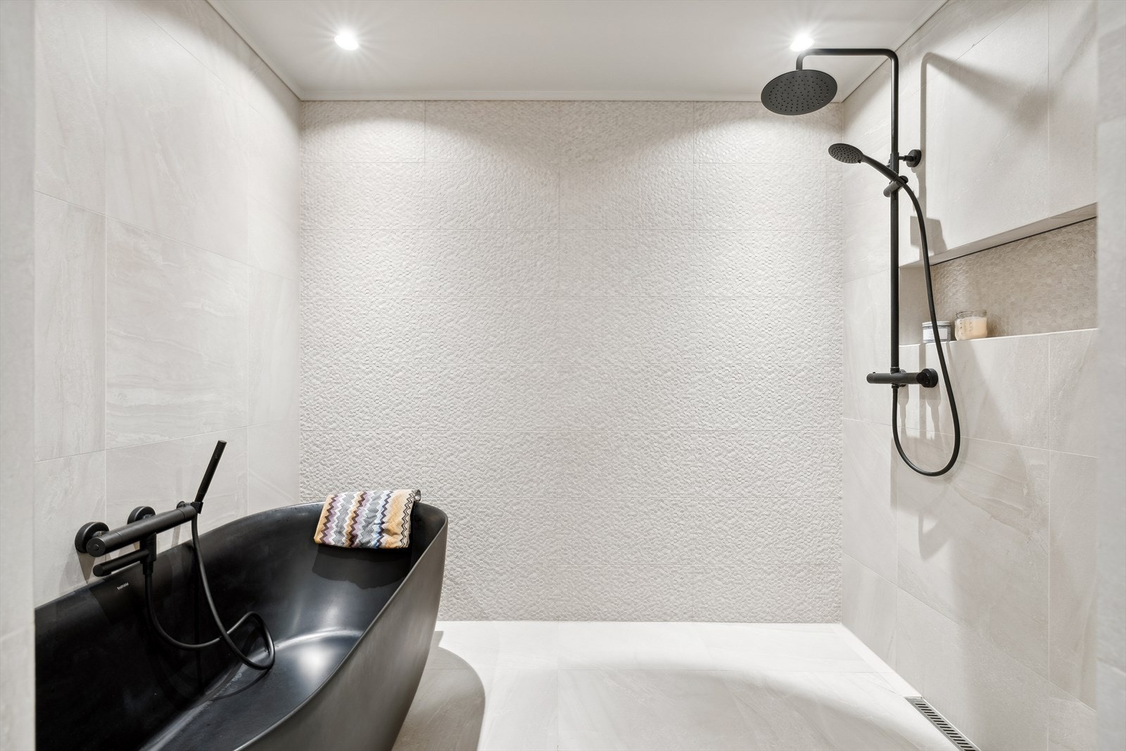 Og egen seksjon for badekar og dusj, innredet med sorte detaljer og nydelige fliser! Galleribilde