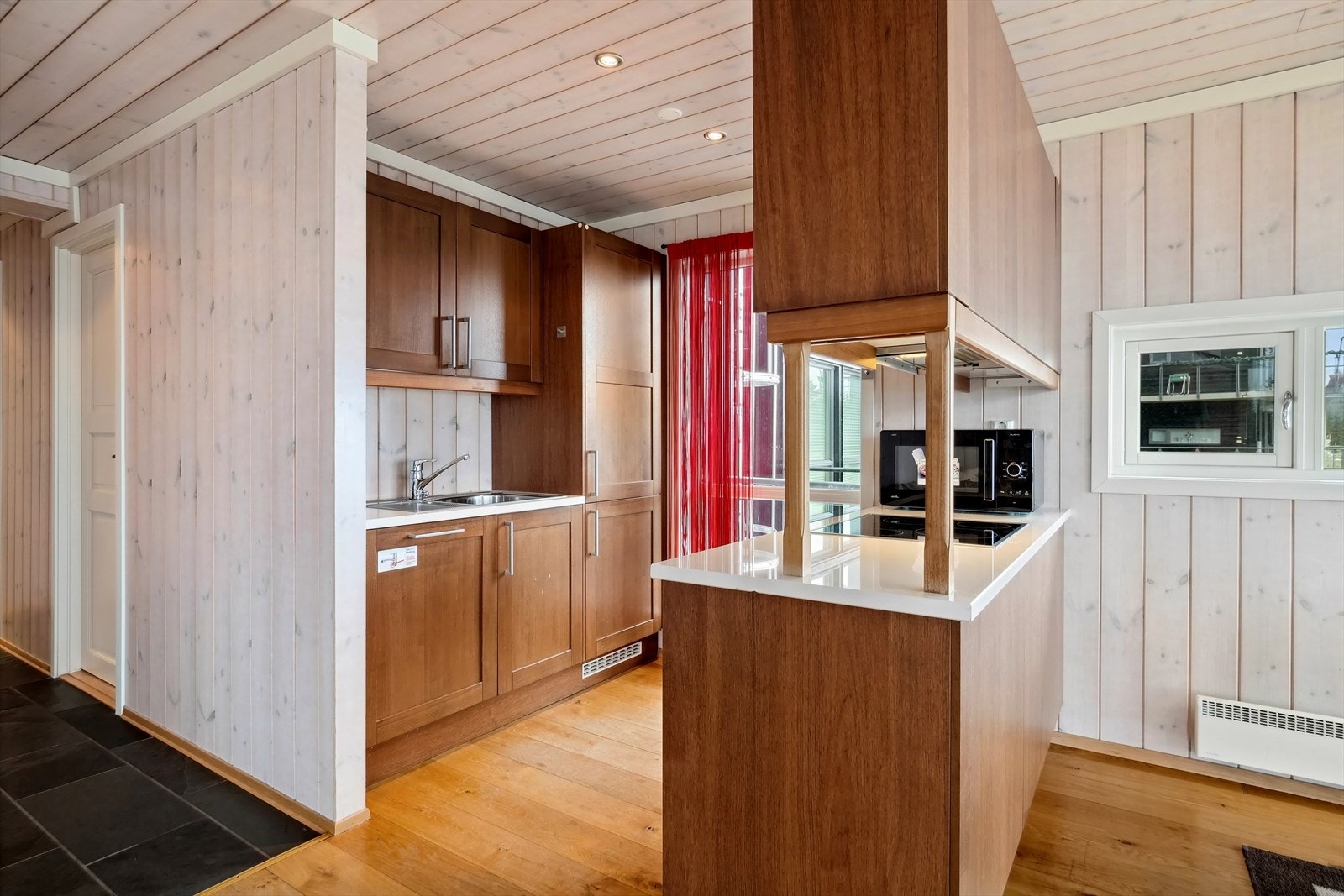 Kjøkkeninnredning med laminerte skrog, fyllingsfronter og stein/komposittplate med kjøkkenkum. Galleribilde