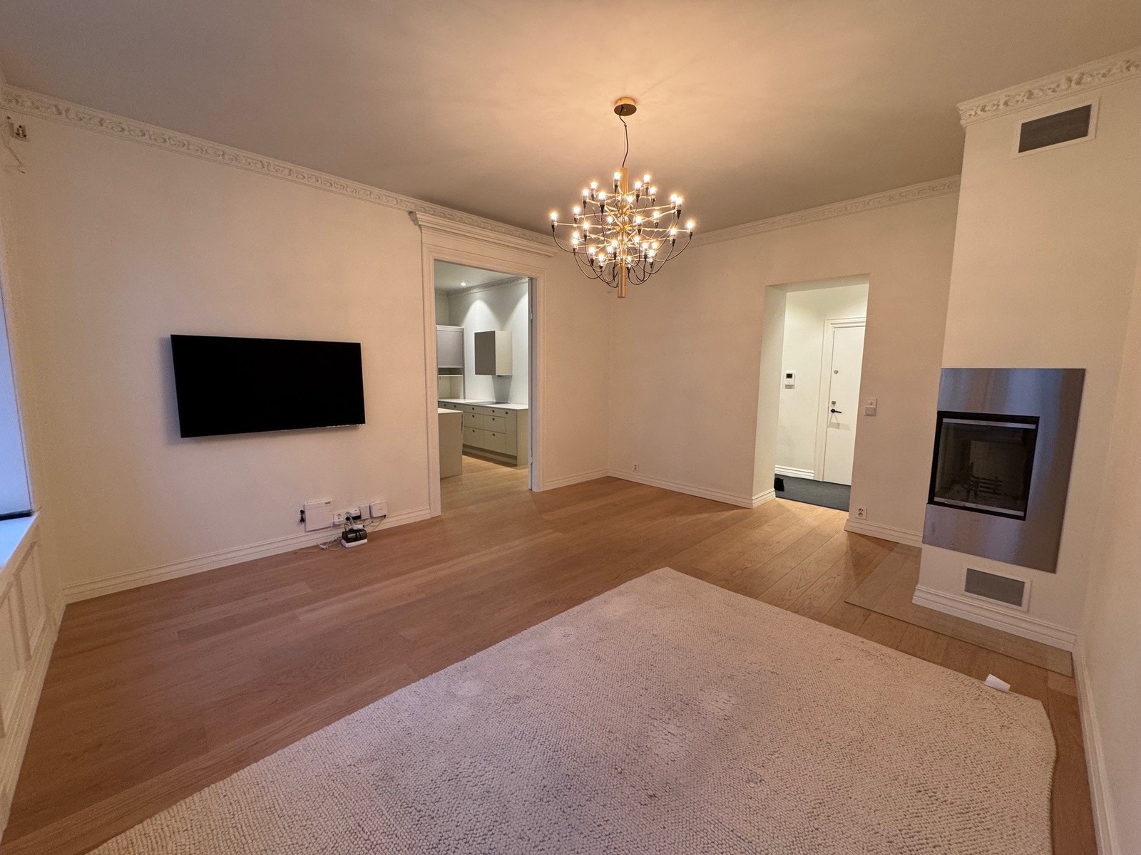 Romslig stue med vegghengt TV og peis Galleribilde