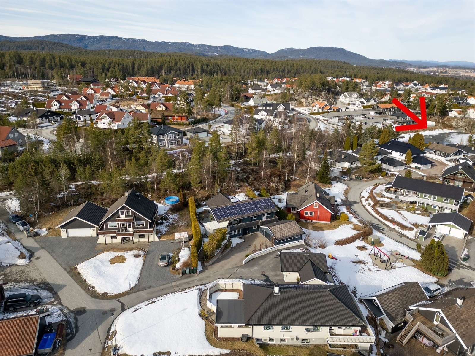 Gangveien bak huset går også ned til fotballbanen (rød pil) som blir vannet til skøytebane om vinteren. Rett nedenfor huset er det en lekeplass med huskestativ, sklie, dumpehuske og sandkasse Galleribilde