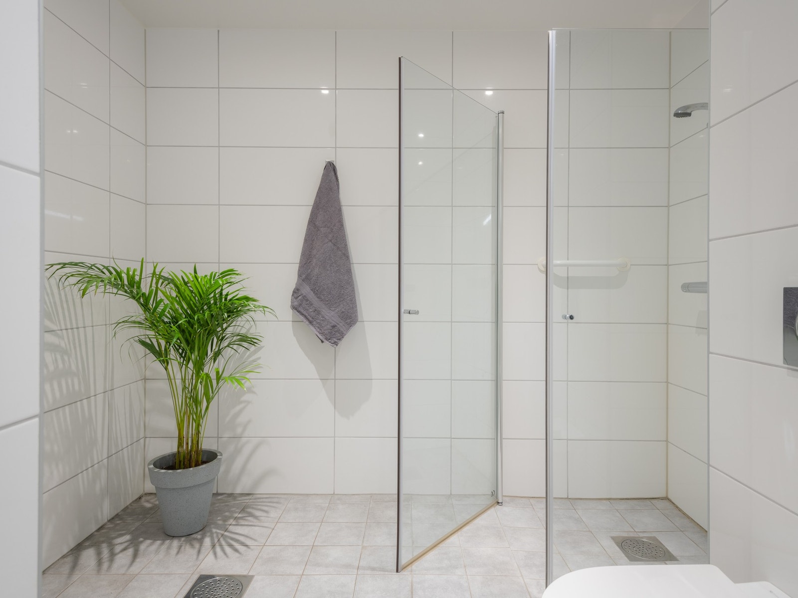 Badet innredet med nedfelt servant, veggfestet toalett, dusjhjørne og opplegg for vaskemaskin. Galleribilde