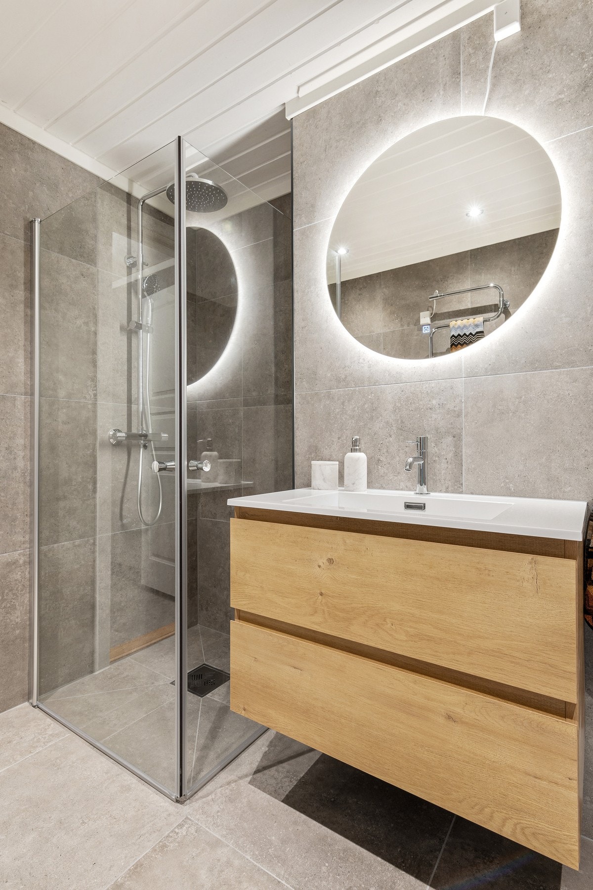 Badet er utstyrt med vegghengt, heldekkende servant, dusjnisje med glassdører med regnfalldusj og vegghengt toalett med innebygget sisterne. Galleribilde