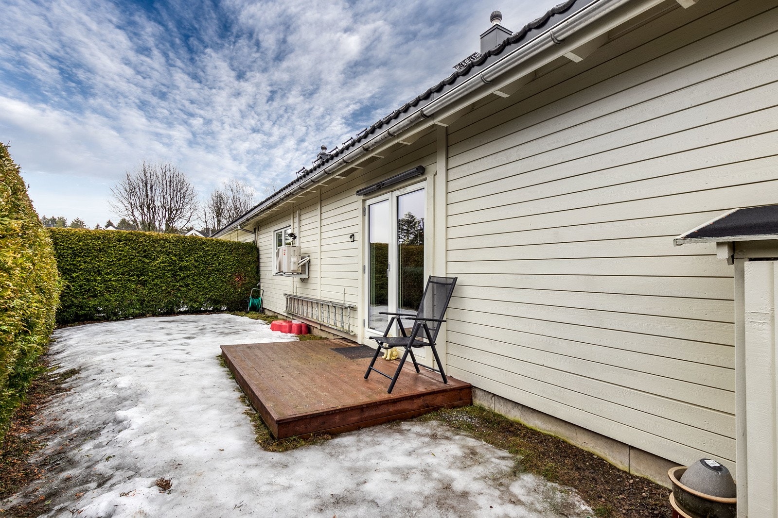 Fra Tv-stuen er det direkte utgang til en skjermet del av hagen med en mindre terrasseplatting. Galleribilde