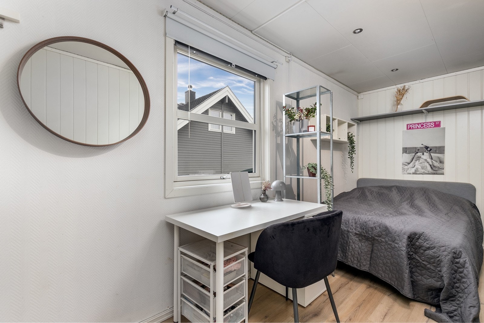 Soverom 2 i boligens 1. etasje har malte veggflater i kombinasjon med smartpanel og laminat på gulv. Et stort vindu slipper inn rikelig med lys. Galleribilde