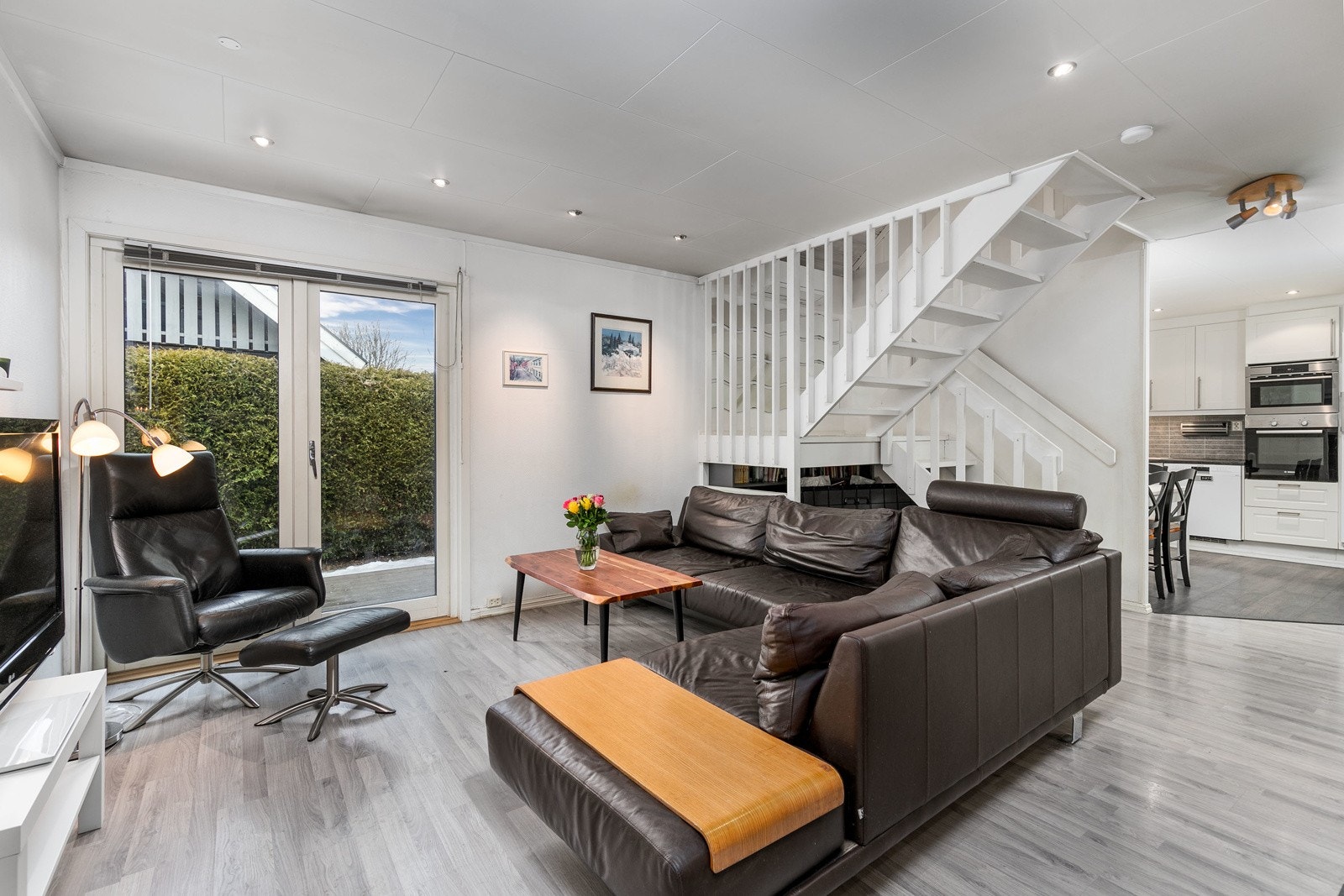 Den åpne Tv-stuen fremstår som meget innbydende i lyse, tidsriktige fargevalg. På gulvet er det lagt gråpigmentert laminat og himlingen er pent lyssatt med downlights. Galleribilde