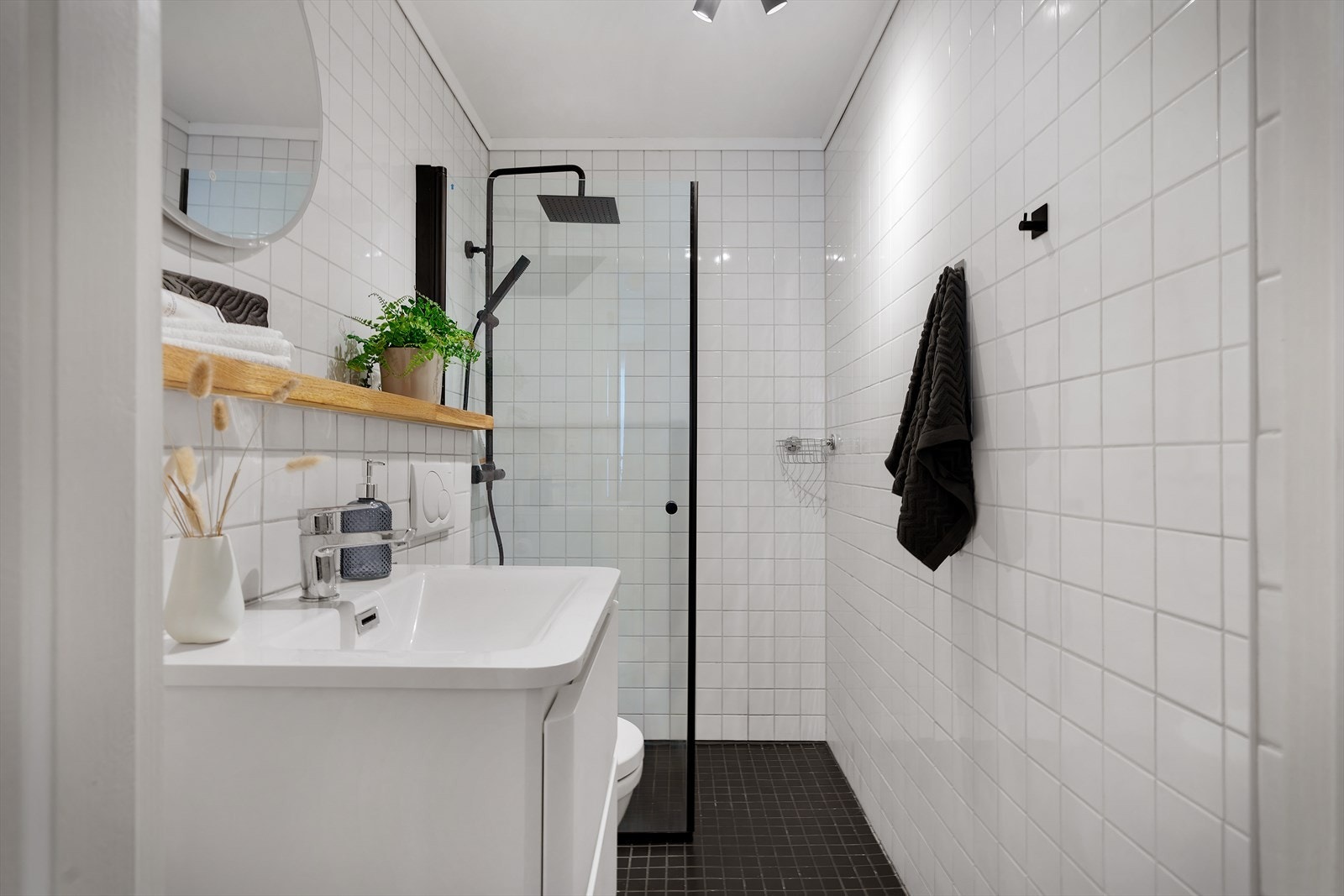 - Badet har et romslig dusjhjørne, servant med underskap, vegghengt toalett og speil med lys - Galleribilde