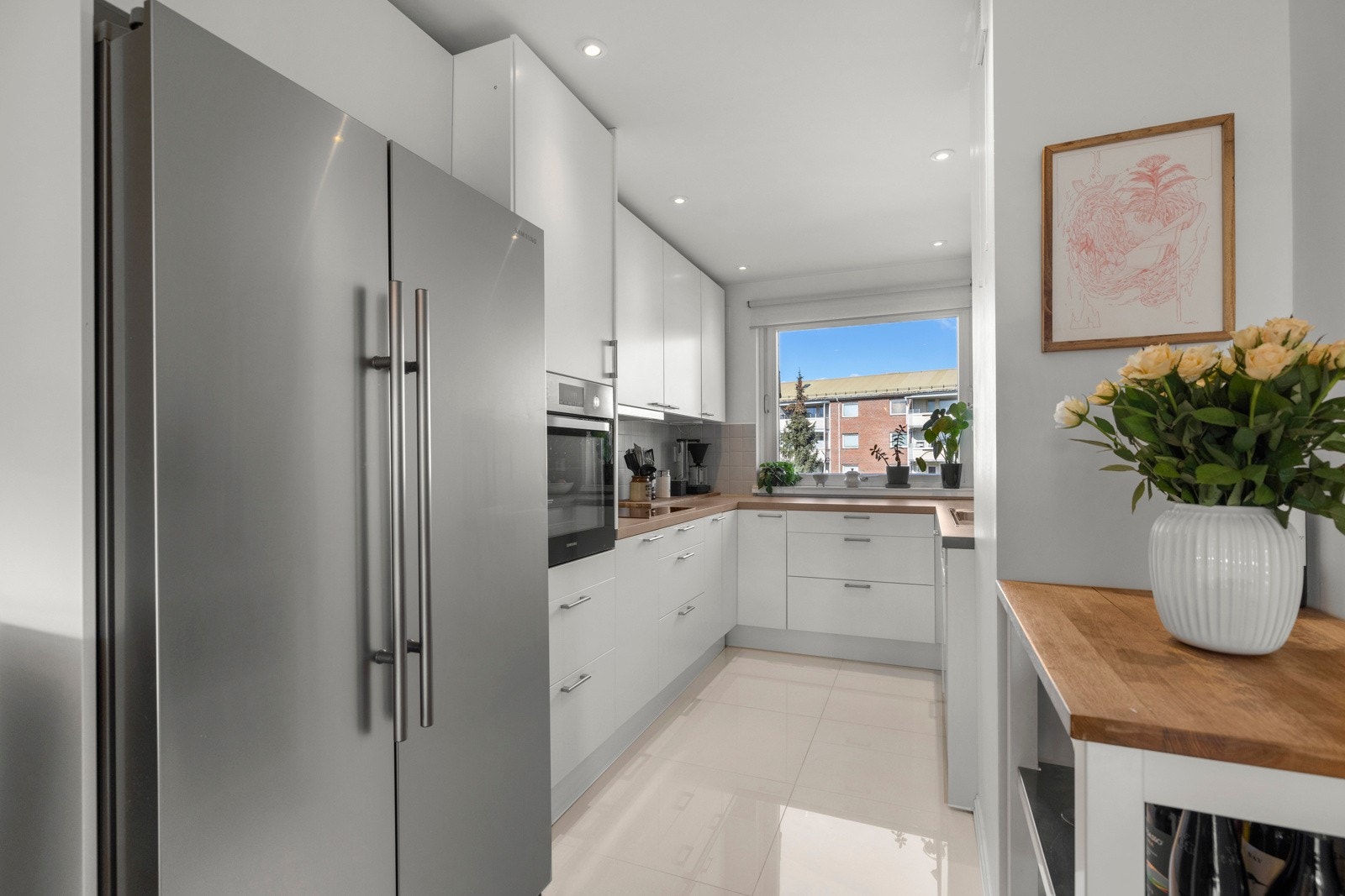 Kjøkkenet har en delvis åpen løsning mot stuen, noe som skaper en luftig og sosial atmosfære. Her er det stor frittstående side-by-side kjøleskap og fryser. Galleribilde