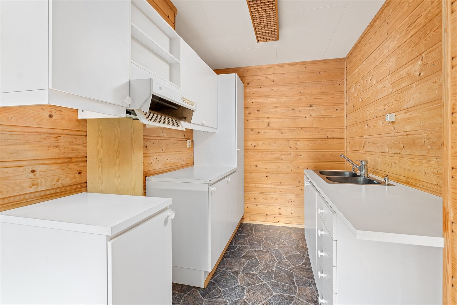 Enkel kjøkkenløsning med innredning med over- og underskap, samt plass for frittstående hvitevarer. Galleribilde