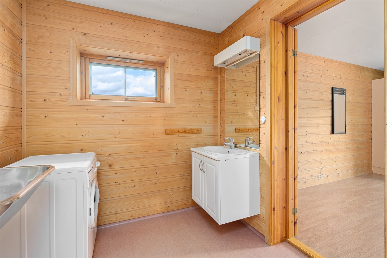 Enkelt bad med servantinnredning, vaskekum og opplegg for vaskemaskin. Galleribilde