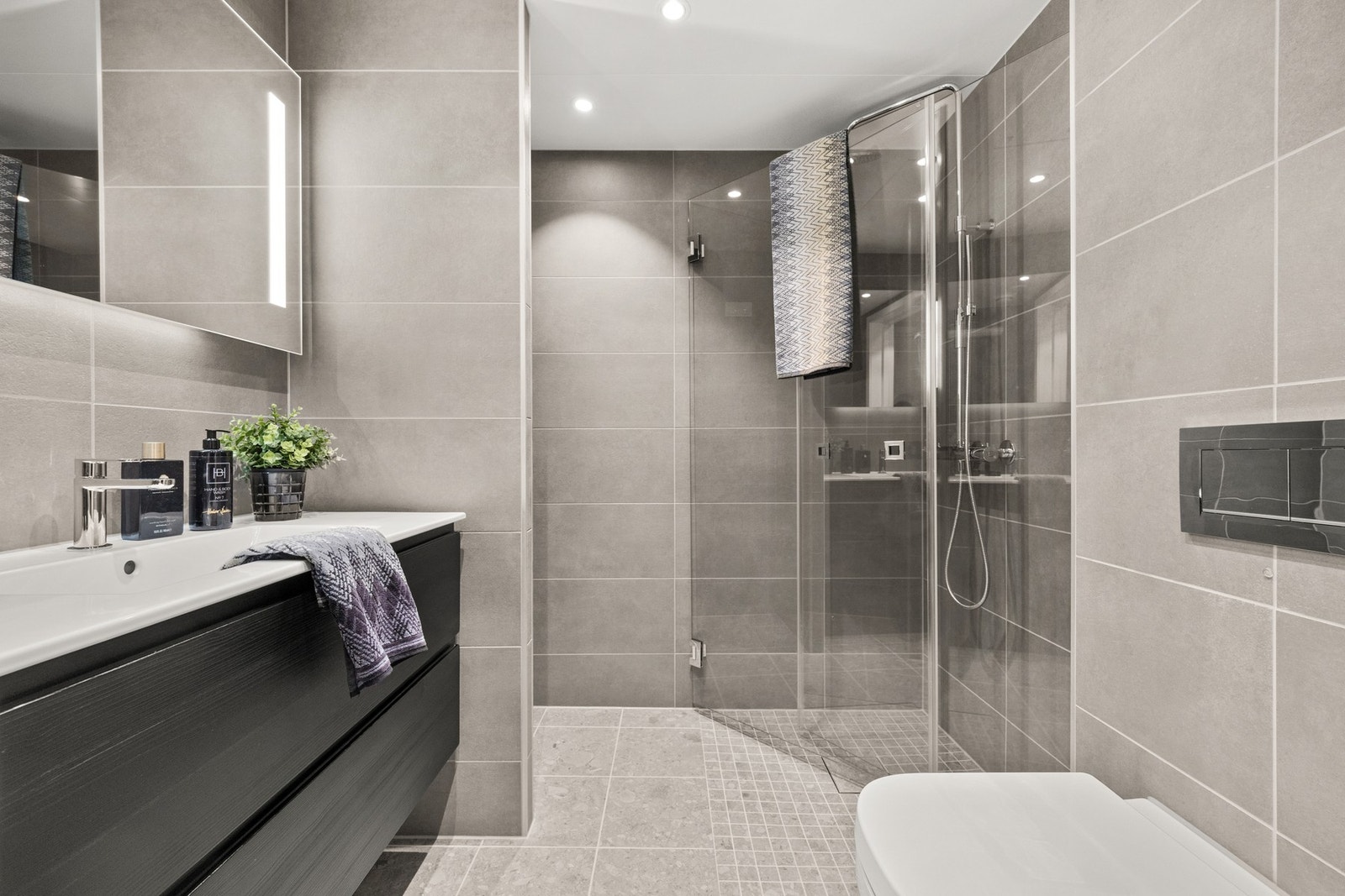 Leiligheten har et delikat flislagt baderom med downlights i himling og varme i gulv Galleribilde