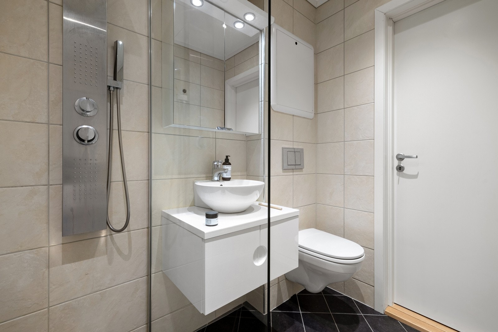 Rommet måler 3 kvm og er innredet med baderomsinnredning, dusj med glassvegger og vegghengt toalett. Galleribilde