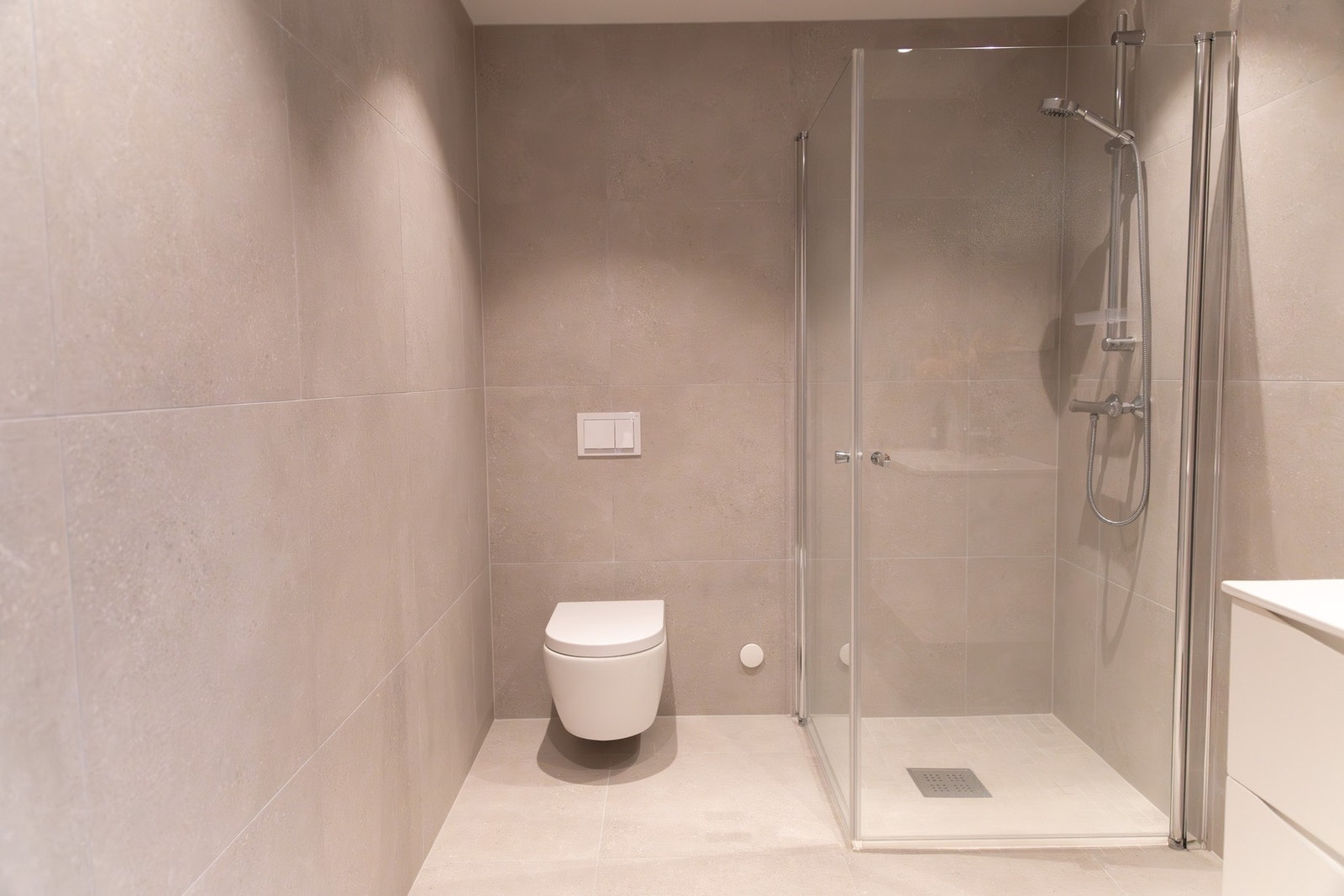 Lyst og delikat bad med servantinnredning, dusjhjørne og toalett. Galleribilde