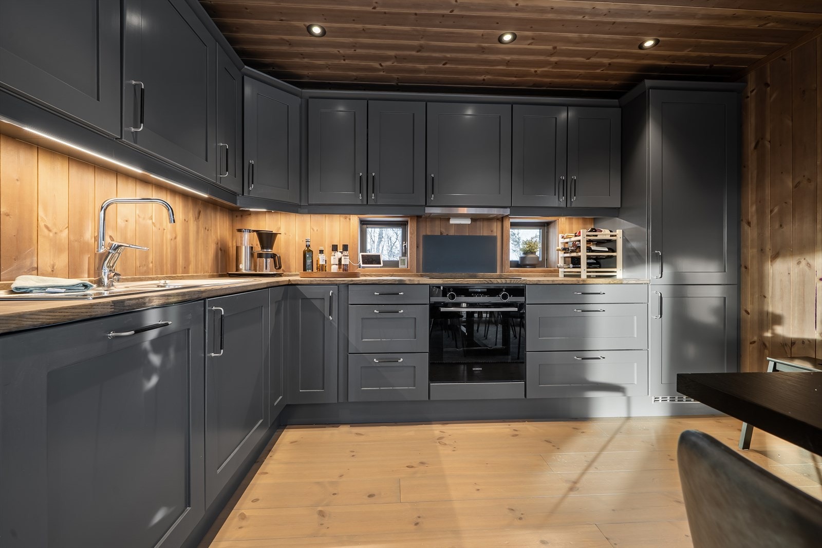 Stilfull og moderne kjøkkeninnredning med grå, profilerte heltre fronter og lekker granitt benkeplate med nedfelt oppvaskkum. Galleribilde