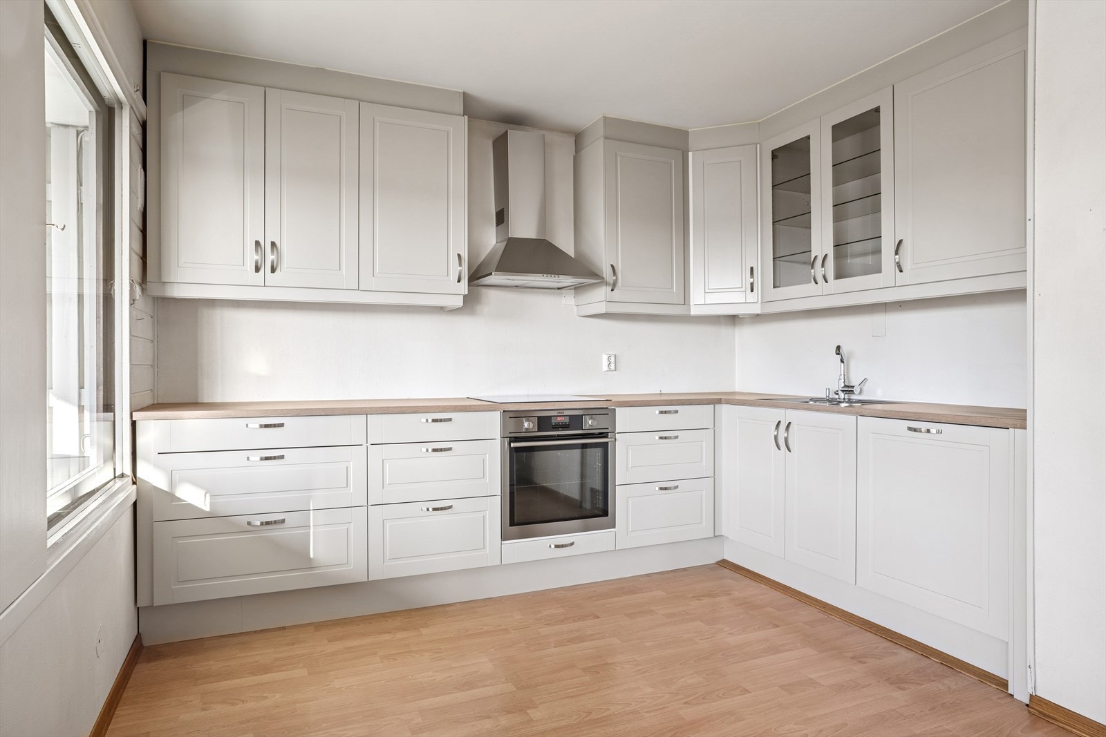 Kjøkkeninnredning med under-/overskap og høyskap, slette fronter, benkeplater av laminat med nedfelt kum og ett-greps blandebatteri. Galleribilde