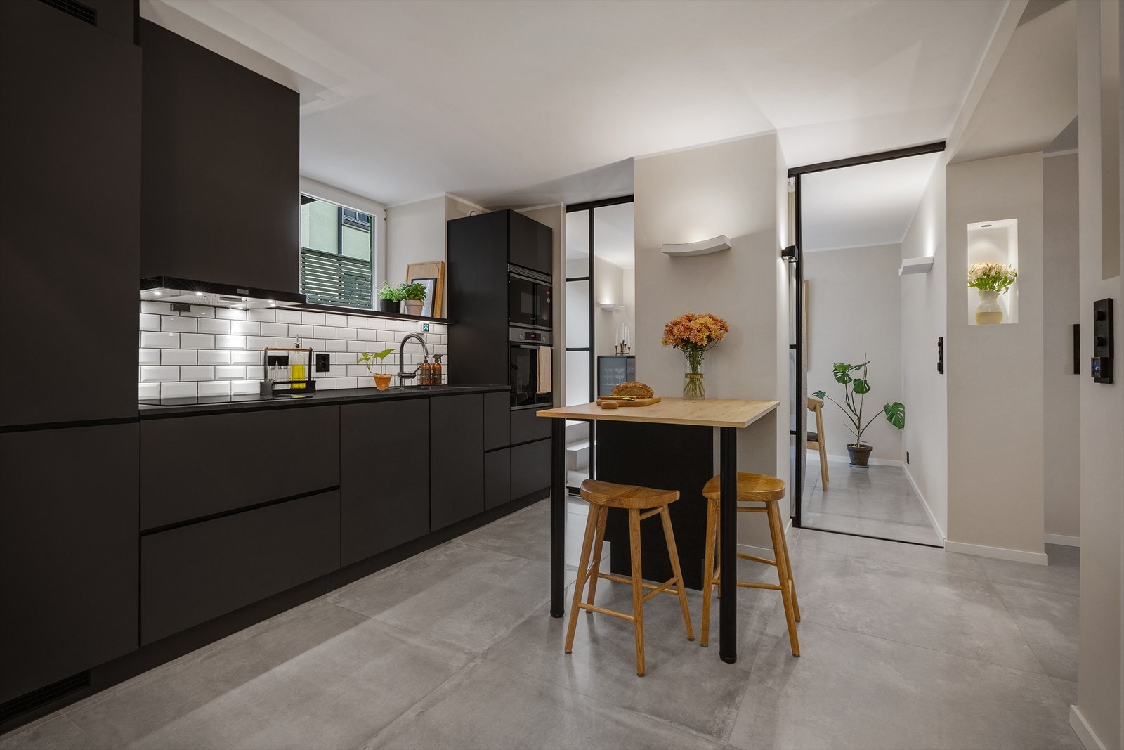 Stilrent kjøkken utført med sorte, slette fronter og benkeplate av laminat med nedfelt vask. Galleribilde