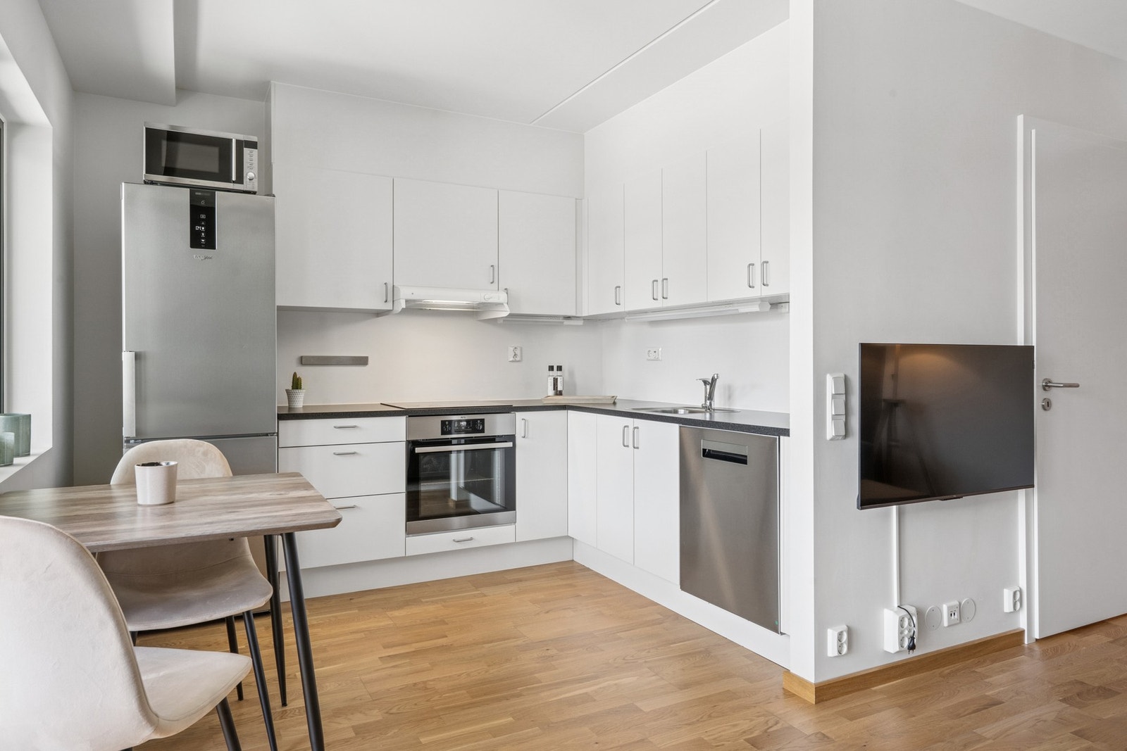 Kjøkkenet ligger i delvis åpen løsning mot stuen. Kjøkkenet har moderne lyse fronter og en mørkere benkeplate som skaper kontrast. Galleribilde