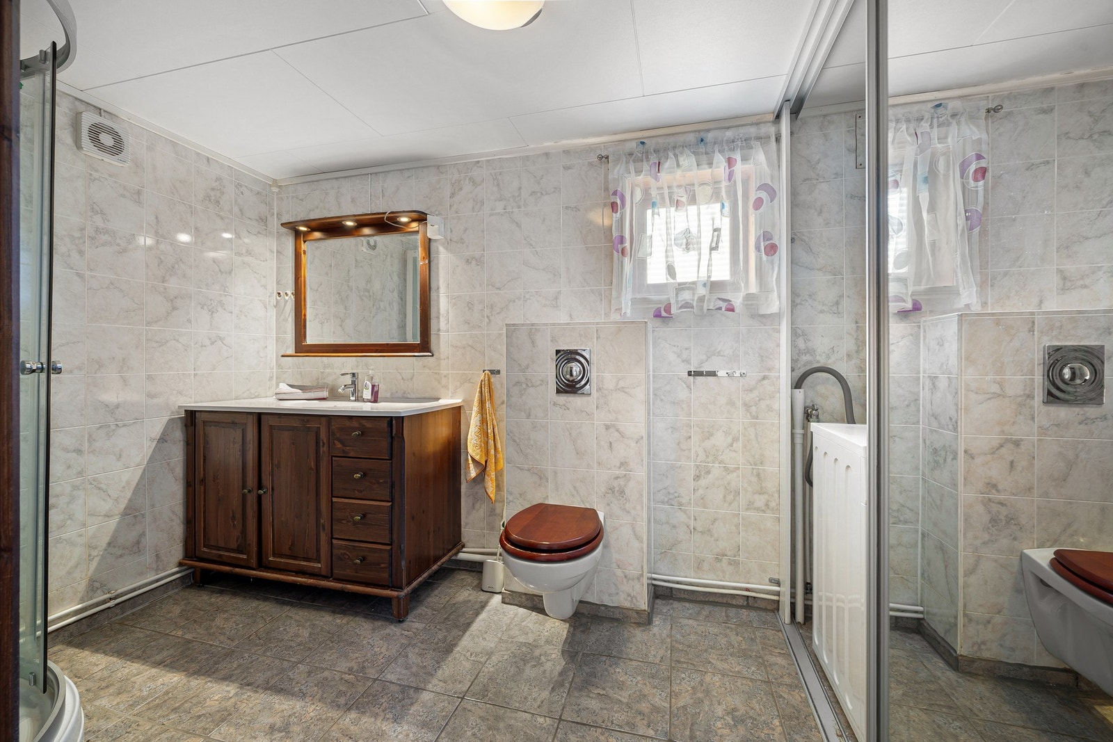 Badet er romslig og inneholder servantinnredning, toalett og dusjkabinett Galleribilde
