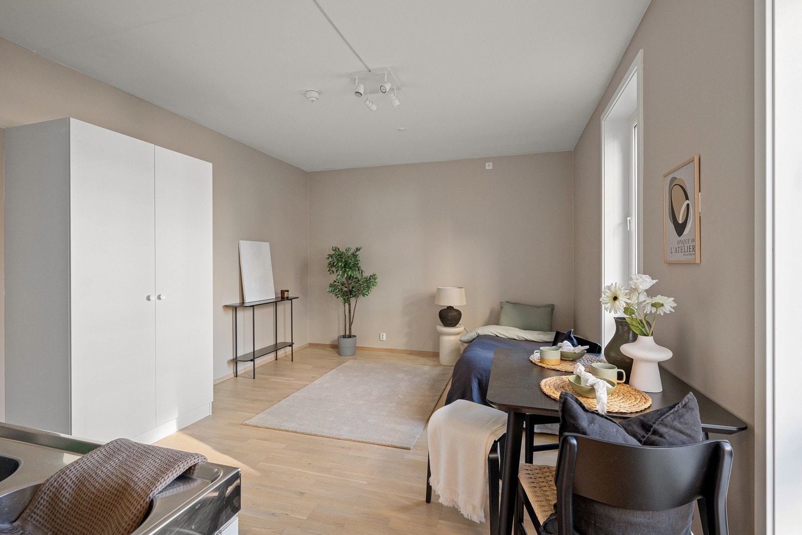 Meget praktisk innredet hybeldel med plass til seng, skap, tv-møblement, spisebord og kjøkkeninnredning Galleribilde