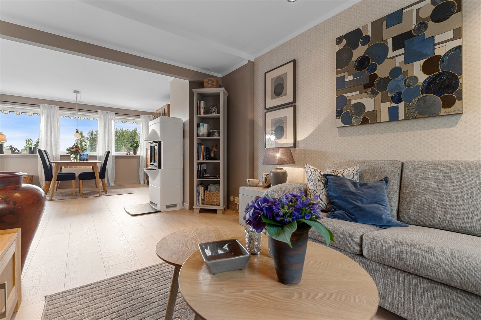 Stilren stue med lys 1-stavs laminat på gulv, slette vegger malt i tidløse fargetoner som skaper en lun stemning til rommet. Galleribilde