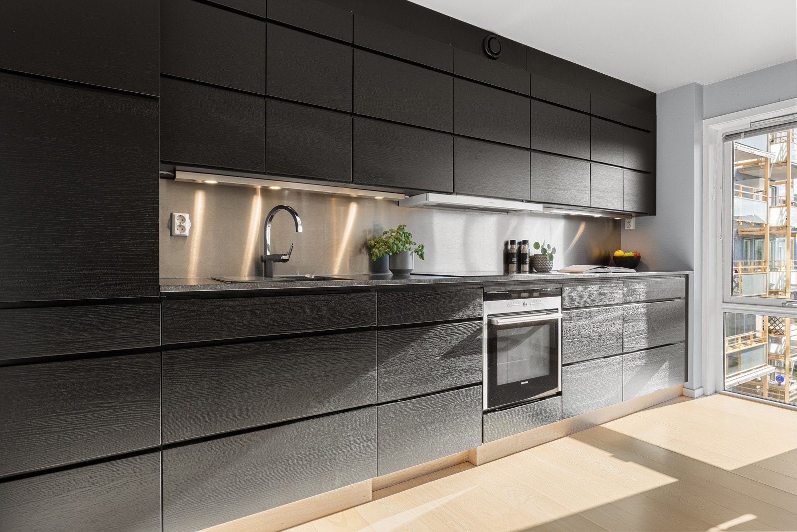 Planlimt kompositt oppvaskkum og plater av rustfritt stål mellom benk og overskap. Oppgradert med ny Induksjonstopp i 2024 og ny kjøl og frys i 2021. Galleribilde