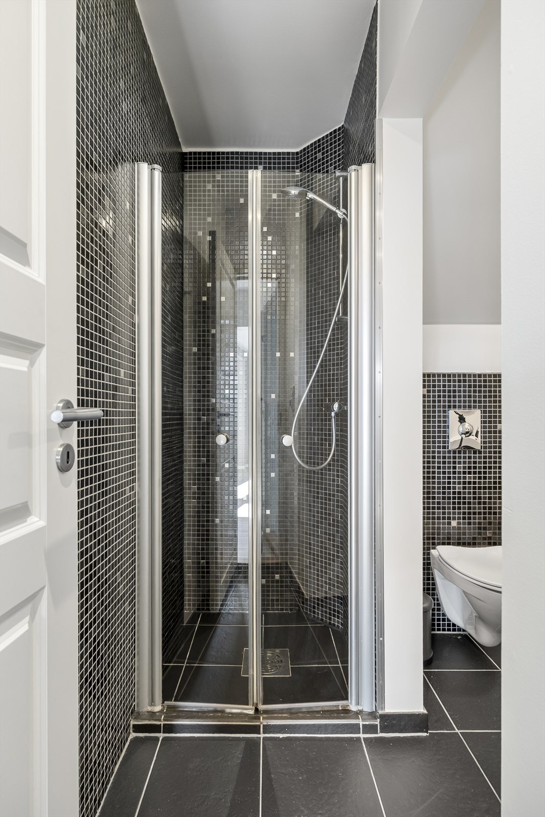 Badet er innredet med servant i baderomsmøbel, veggmontert toalett og dusj. Galleribilde