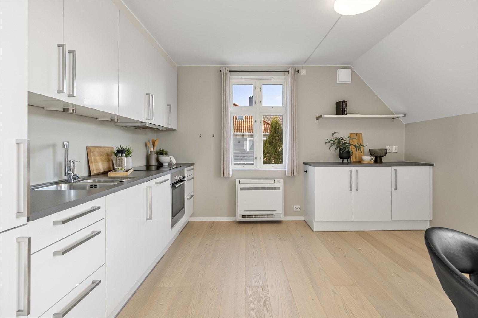 Tidløs kjøkkeninnredning med hvite, glatte fronter og laminat benkeplate. Det er godt med skap- og benkeplass. Galleribilde