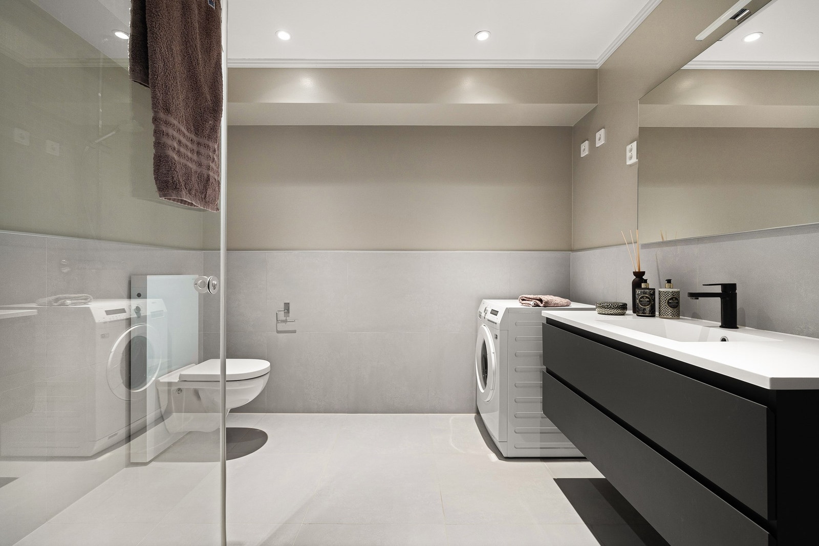 Romslig og stilfullt bad, med storformat fliser lagt på gulvet og opp til brystningshøyde på vegger. Galleribilde