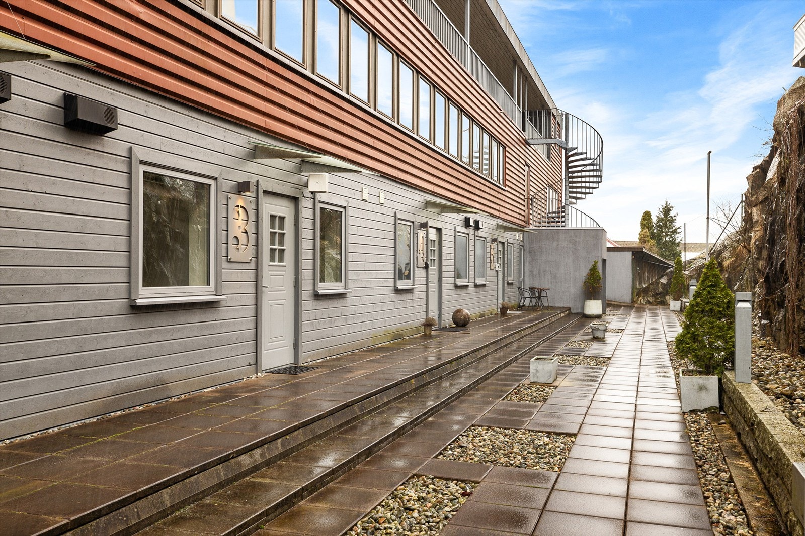 Leilighetens inngangsparti er tilbaketrukket og skjermet fra omgivelsene. Her er det formiddagssol sommerstid. Galleribilde