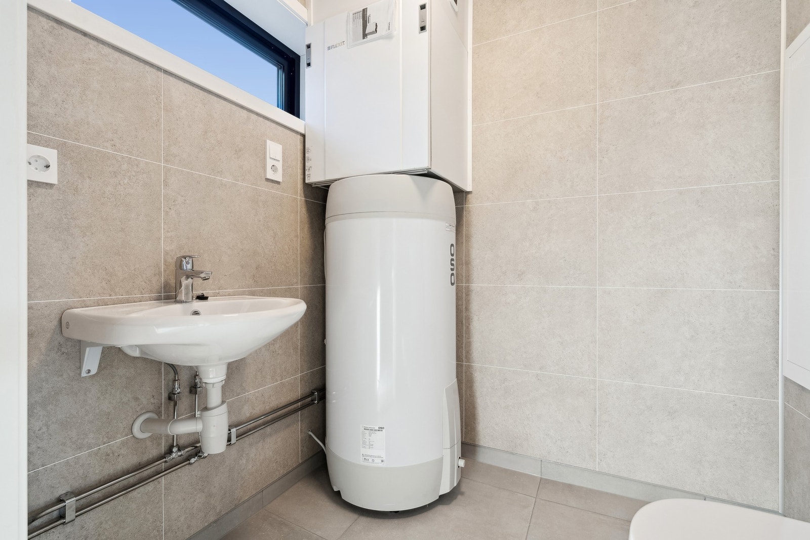 Eget vaskerom i 1. etasjen med toalett, servant, varmvannsbereder, rørfordelingsskap og ventilasjonssystem. Galleribilde