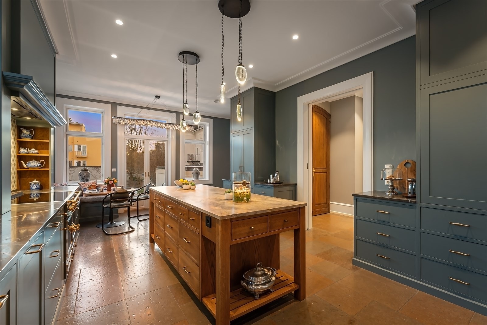 Stort snekkertilpasset kjøkken med øy og spiseplass - masse lysinnfall fra vinduer og utgang haven Galleribilde