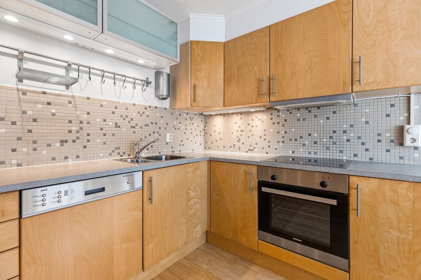 Kjøkkenet er utstyrt med integrerte hvitevarer som stekeovn med keramisk platetopp, oppvaskmaskin, kjøleskap med frysedel og ventilator Galleribilde