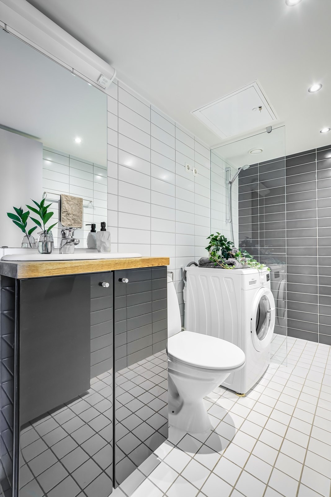 Baderommet er stilrent med fliser på vegger og senket innvendig tak med innfelt lys. Baderommet har flislagt gulv med nedsenket dusjsone og elektriske varmekabler Galleribilde