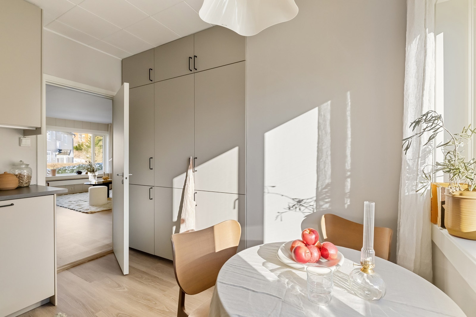 Kjøkkeninnredning med matte, lyse fronter og moderne sorte detaljer. Her er det montert benkeskapsbelysning og stikkontakt over kjøkkenbenk Galleribilde