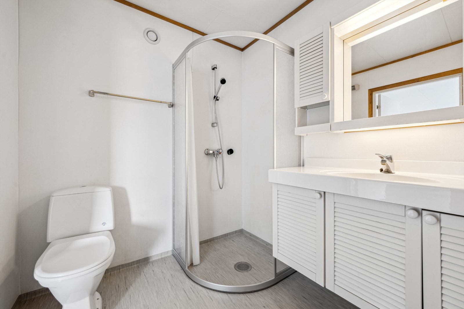 Badet er innredet med vegghengt servantskap med ovenpåliggende servant med armatur. Speil og belysning med overskap på vegg. Galleribilde