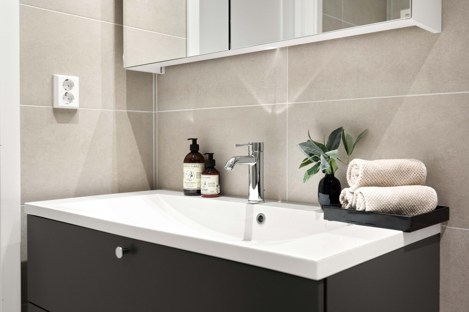 Rommet har baderomsinnredning fra den anerkjente Sigdal-serien i modellen Lilje. Modellen er designet med romslige skuffer og en heldekkende vask for en sømløs finish. Over vasken leveres et praktisk speilskap, perfekt tilpasset innredningens bredde. Galleribilde