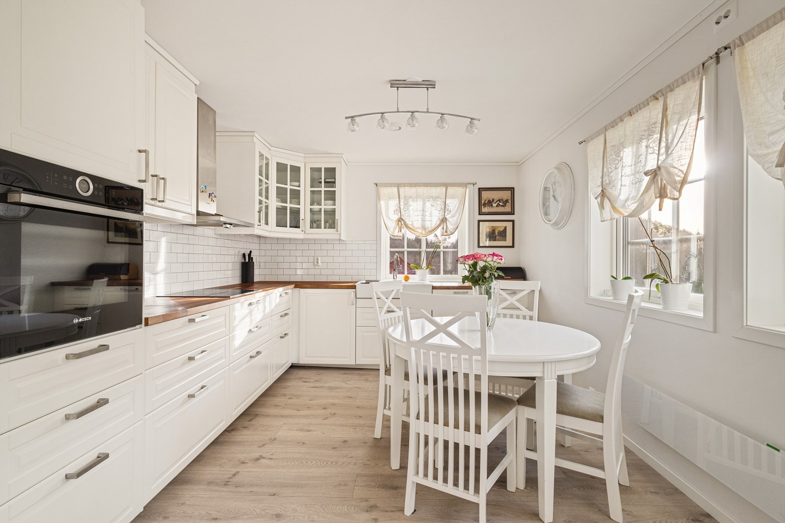 Kjøkkenet har en stilren design med hvite, profilerte fronter og rikelig med lagringsplass i takhøye overskap samt underskap Galleribilde