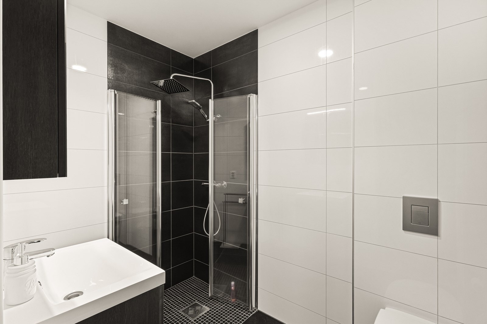 Badet er pent innredet med vegghengt toalett, dusjhjørne m/glassdører og servant med innredning/speilskap/belysning Galleribilde