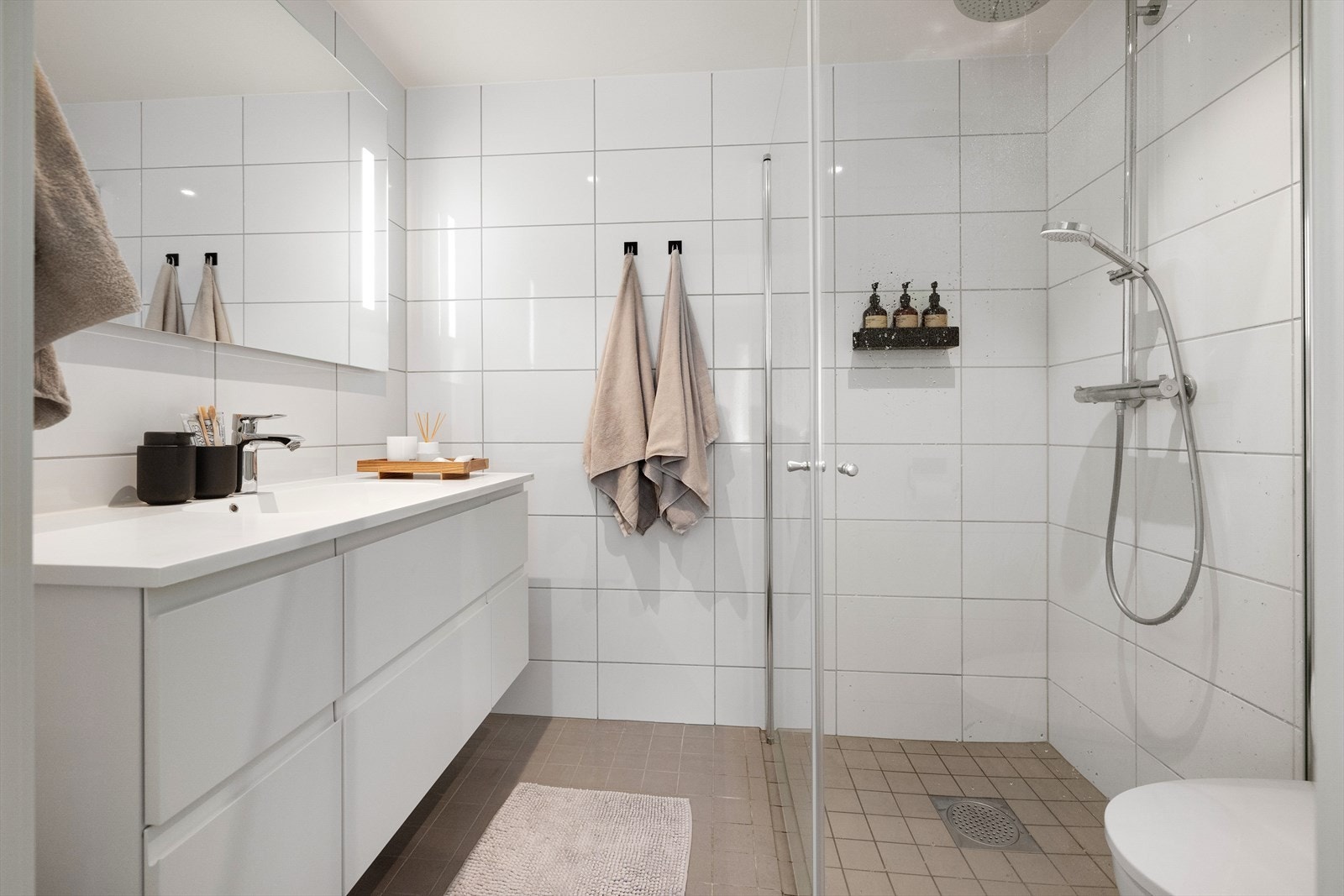 Det er veggmontert toalett og dusjvegger i herdet glass med innfellbare dusjvegger. Det er regnfallsdusj samt håndholdt spyler i dusjen Galleribilde