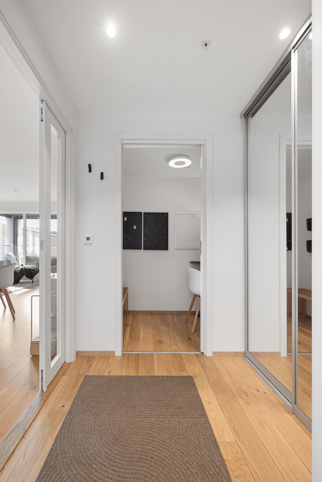 Stilren entré med malte, lyse flater, pusset og malt himling i betong samt gulv av 1-stavs parkett. Det varmefolie i gulv samt en romslig skyvedørsgarderobe som har god plass til oppbevaring av yttertøy Galleribilde