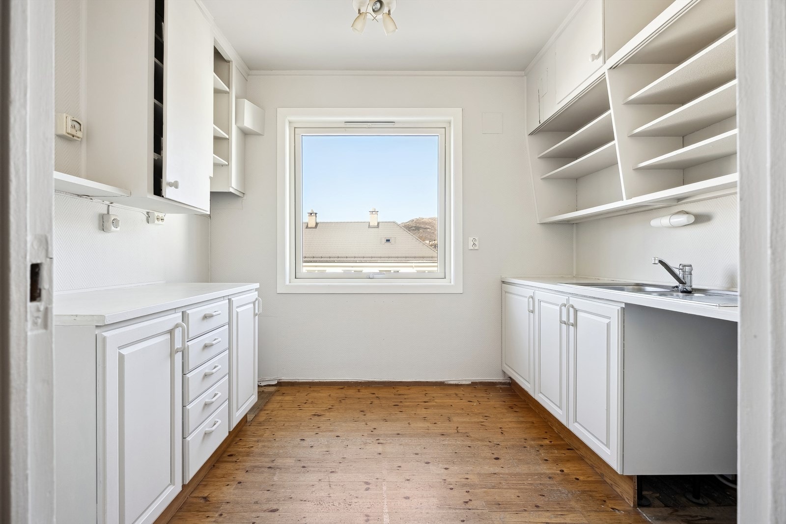 Eldre kjøkkeninnredning med slette og profilerte fronter, laminert benkeplate og stålvask. Det er godt med benk- og skapplass Galleribilde