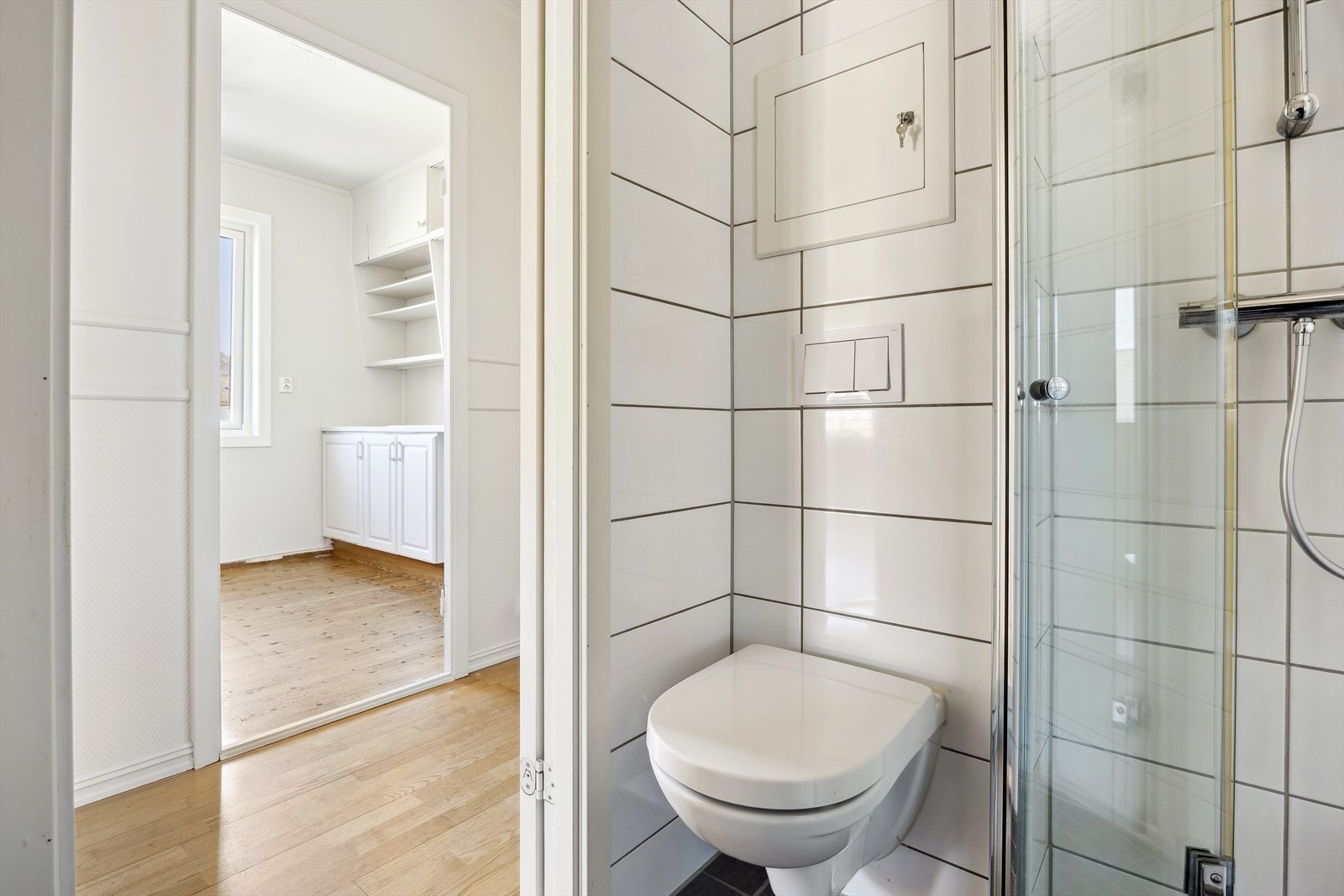 Badet er innredet med servant med skapinnredning, dusj med vendbare dusjdører og vegghengt toalett Galleribilde