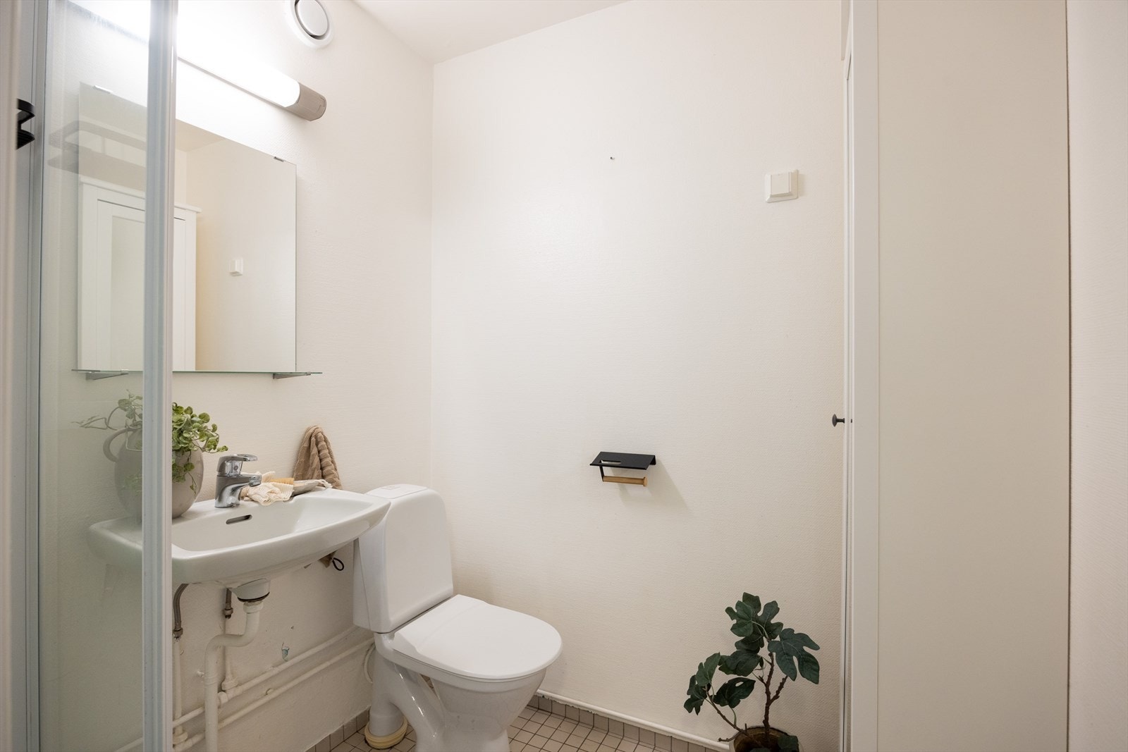 Eldre bad med flislagt gulv, malt strie på vegger, stråleovn, avtrekk, speil, armatur, servant, dusjkabinett og toalett Galleribilde