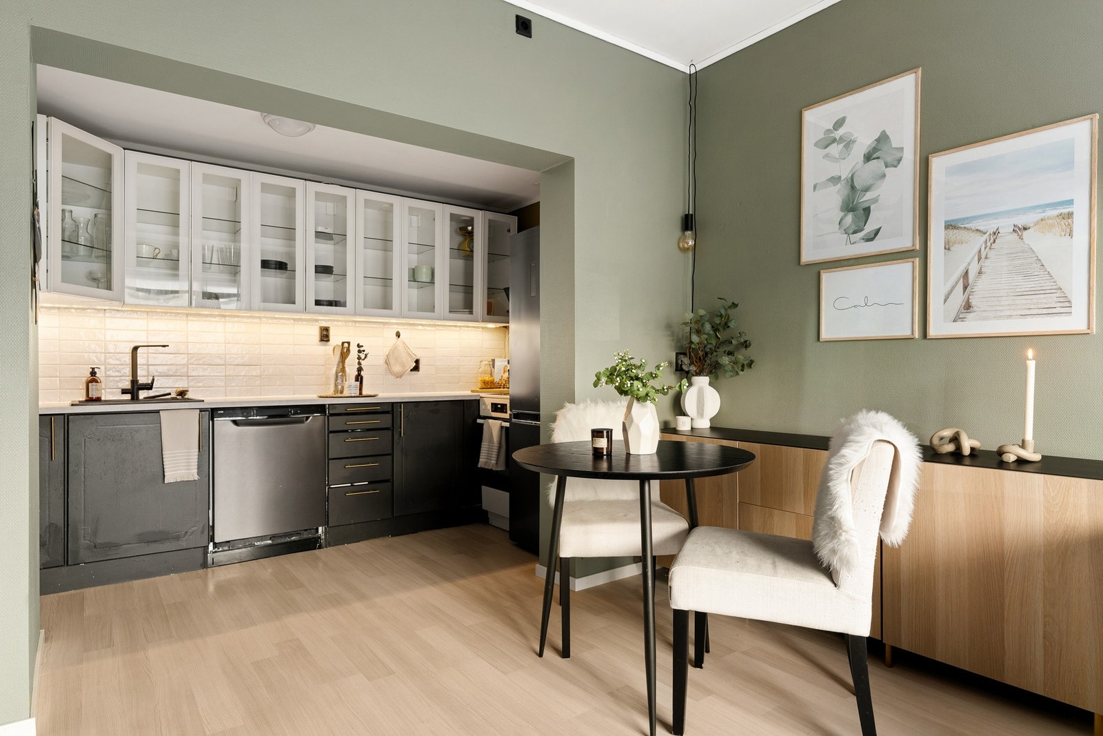 Kjøkken bestående av overskap med glassdører, folierte skrog med slette fronter og laminert benkeplate. Flis på vegg over benkeplate. Galleribilde