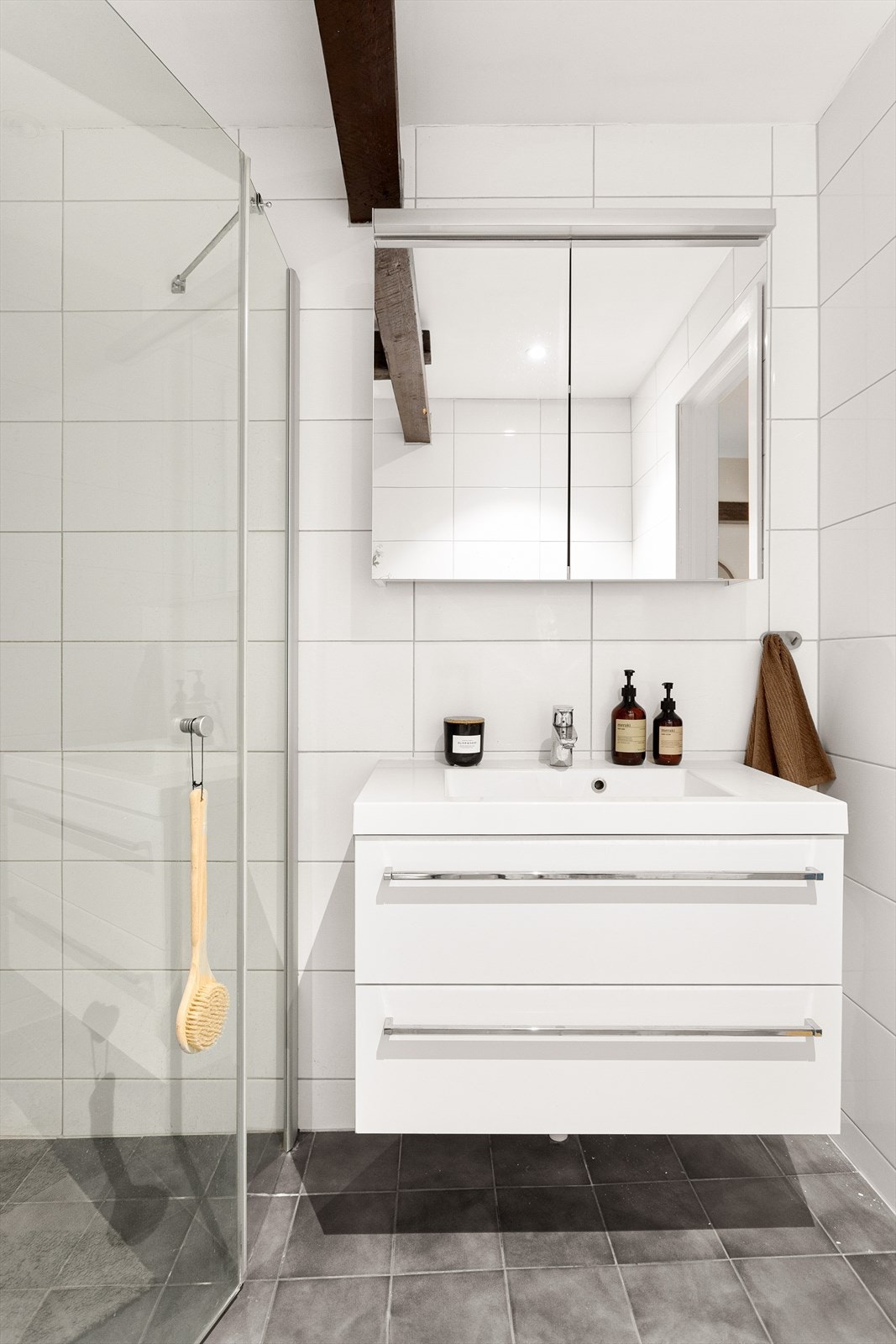 Baderommet er innredet med vegghengt klosett, servant nedfelt i innredning og dusjhjørne med svingbare glassdører. Galleribilde