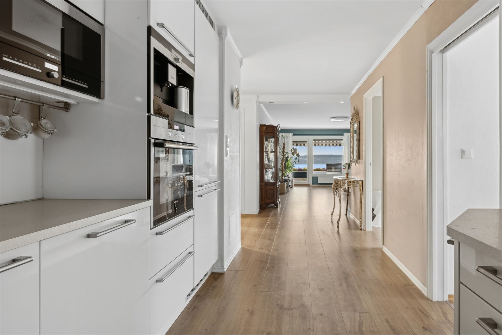 Av integrerte hvitevarer finner du platetopp, stekeovn (skiftet i 2022), mikrobølgeovn, oppvaskmaskin, kaffemaskin samt kjøle- og fryseskap. Løsningen er både stilren og funksjonell, perfekt for en effektiv og hyggelig matlagingsopplevelse. Galleribilde