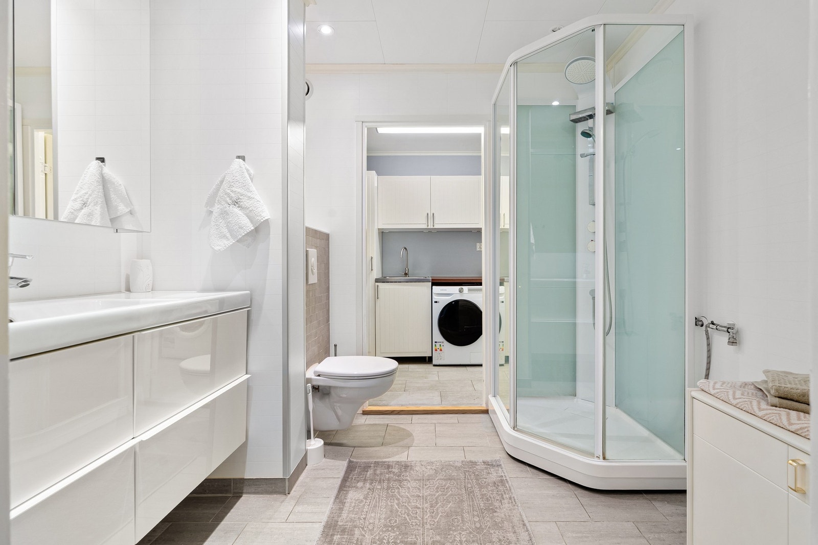 Pent bad med fliser på gulv, baderomsplater på vegg og gulvvarme. Galleribilde