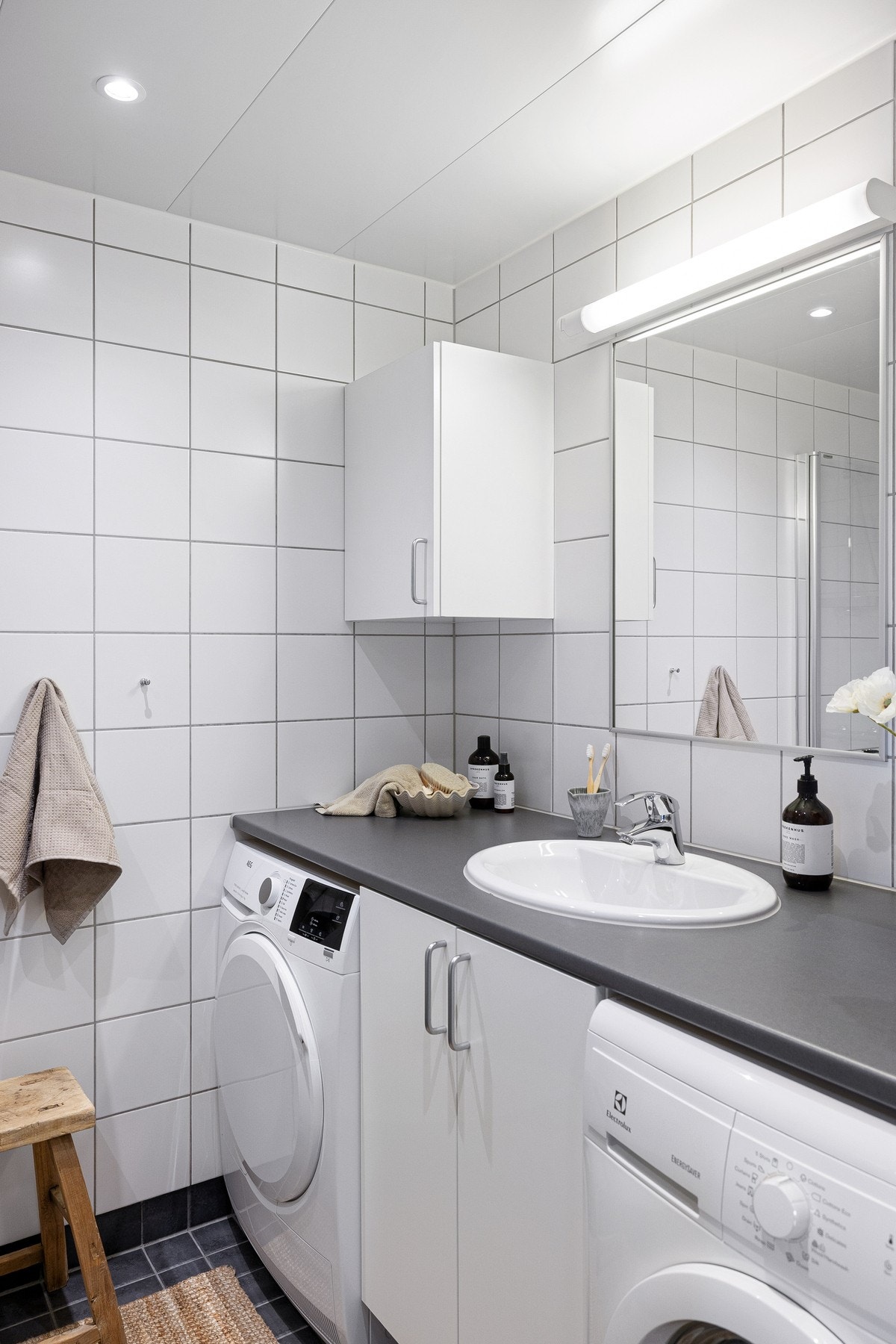 Under en praktisk benkeplate finnes opplegg og plass for både vaskemaskin og tørketrommel, noe som gjør rommet velegnet for en effektiv og funksjonell hverdag. Galleribilde