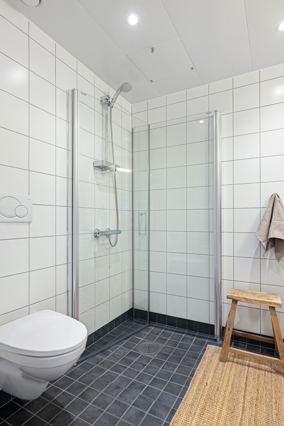 Badet er utstyrt med dusjhjørne med innfellbare glassdører og toalett. Galleribilde