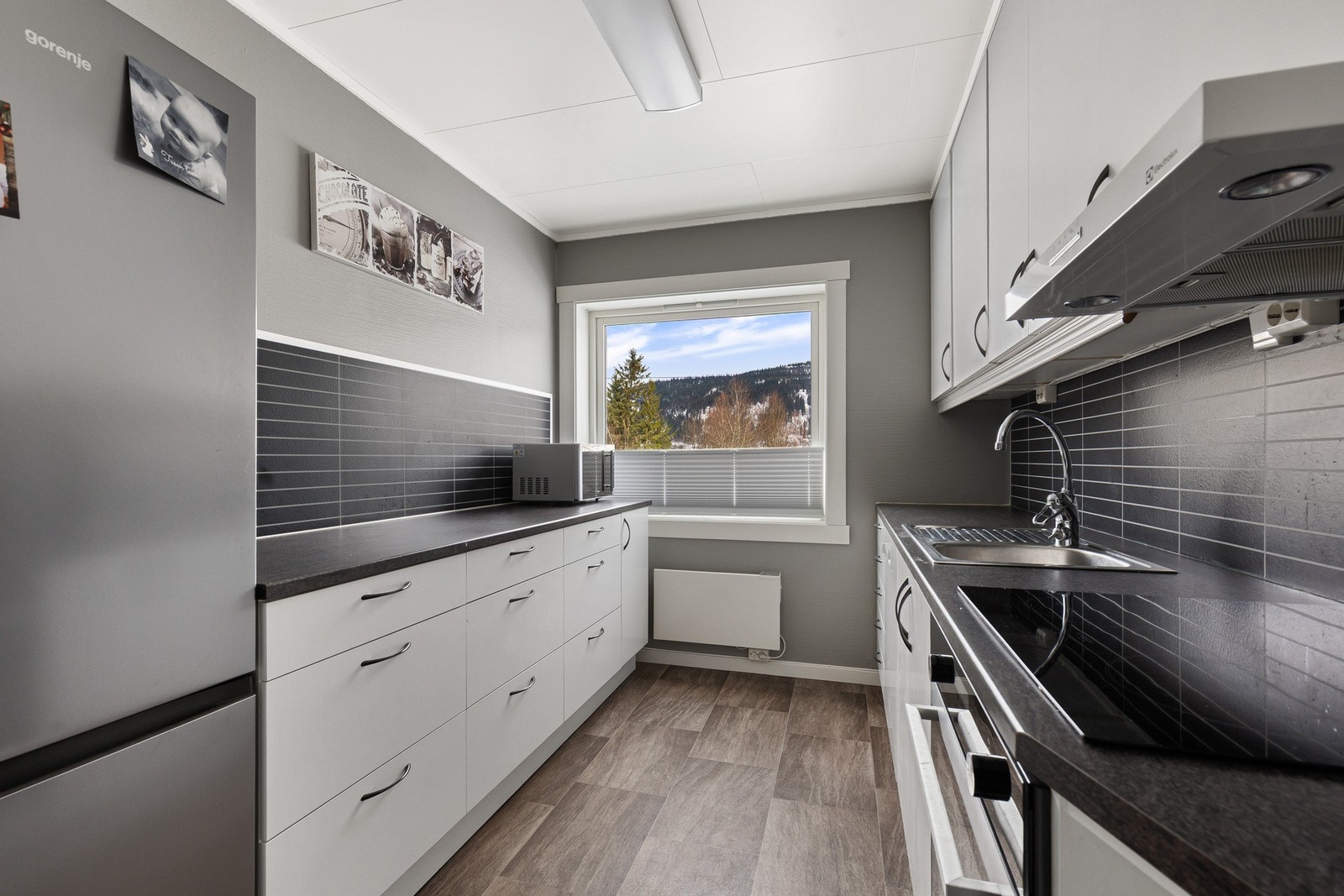 Kjøkkenet er pent og holder et tidløst preg med sine hvite slette fronter Galleribilde