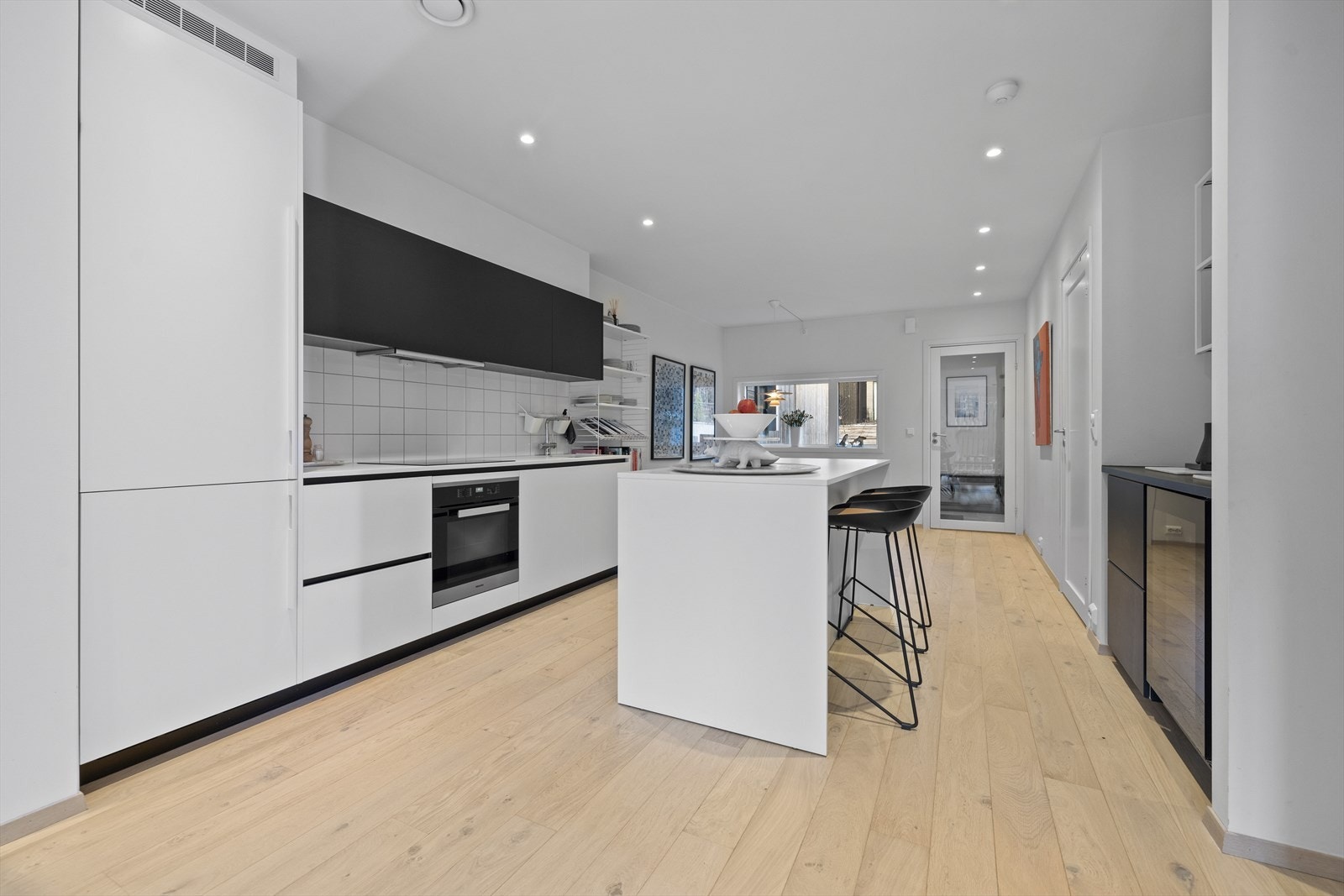 Hvite glatte fronter på skuffer og skap, samt sorte fronter på overskap. Benkeplate med underlimt oppvaskkum i rustfritt stål Galleribilde